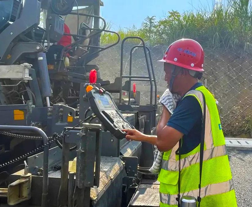 城開(kāi)高速2021年通車(chē)段路面施工現(xiàn)場(chǎng)，瀝青攤鋪工人加緊施工。重慶高速集團(tuán)供圖