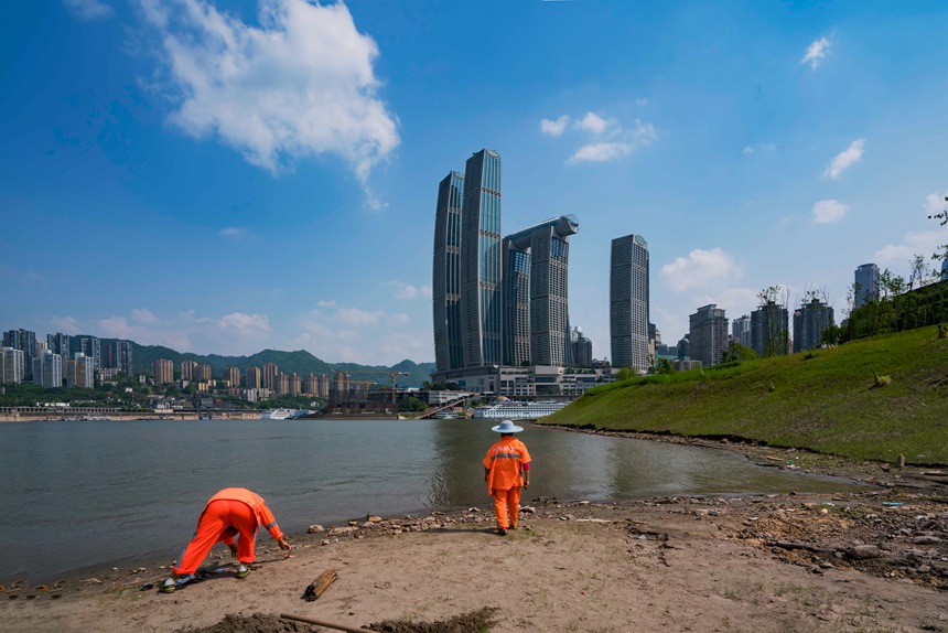 環(huán)衛(wèi)工人冒著烈日清理河邊垃圾。黃進(jìn)攝