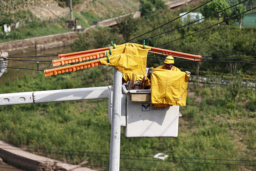 電力公司工作人員在電線上鋪上絕緣毯。國網(wǎng)重慶市電力公司供圖