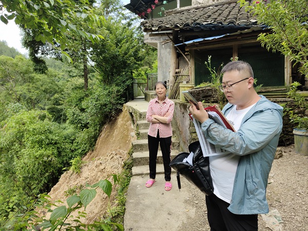 《群眾安全無小事》。6月15日，黔江區(qū)金溪規(guī)劃和自然資源所會(huì)同107地質(zhì)隊(duì)總工路政坤（右）在金溪鎮(zhèn)清水村祝家?guī)r查看農(nóng)戶屋角發(fā)生的局部垮塌險(xiǎn)情，并提出專業(yè)意見。李偉攝