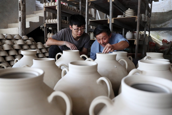 羅達(dá)川（左）跟劉沛良學(xué)檢查陶坯的質(zhì)量。黔江區(qū)委宣傳部供圖
