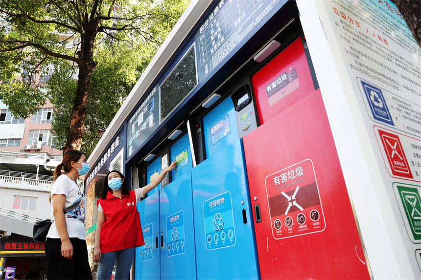 在生活垃圾分類服務(wù)驛站，管理員（右）在給市民講解使用垃圾智能分類的方法。楊敏攝
