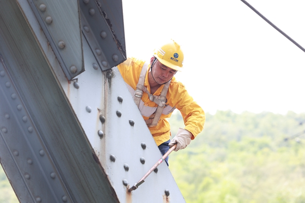 烈日下鮮志榮爬上鋼梁大橋檢查連接螺栓。晏濤攝