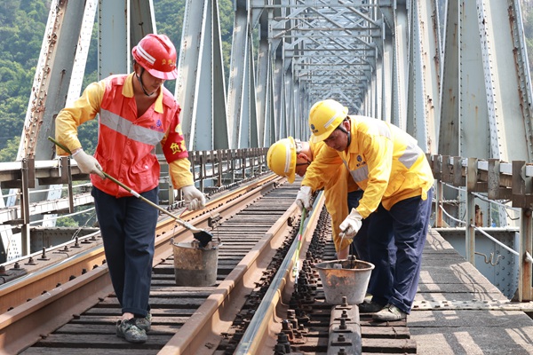 烈日下重慶工電段職工正在對(duì)襄渝鐵路北碚嘉陵江鋼梁大橋枕木扣件螺栓進(jìn)行涂油。晏濤攝