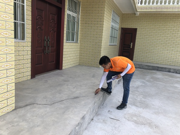 《清晨的野外巡查》。7月9日早上8時,黔江區(qū)駐守地質(zhì)隊員潘笑天在五里鎮(zhèn)嚴家河進行巡查，現(xiàn)場調(diào)查記錄滑坡體上房屋的變形情況。  曹志遠攝