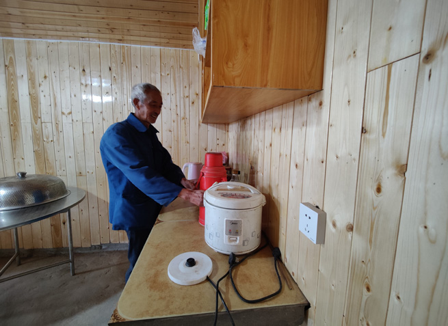 杉板裝飾的屋內(nèi)，老黨員正熱情地給客人們倒茶。徐俊聰攝