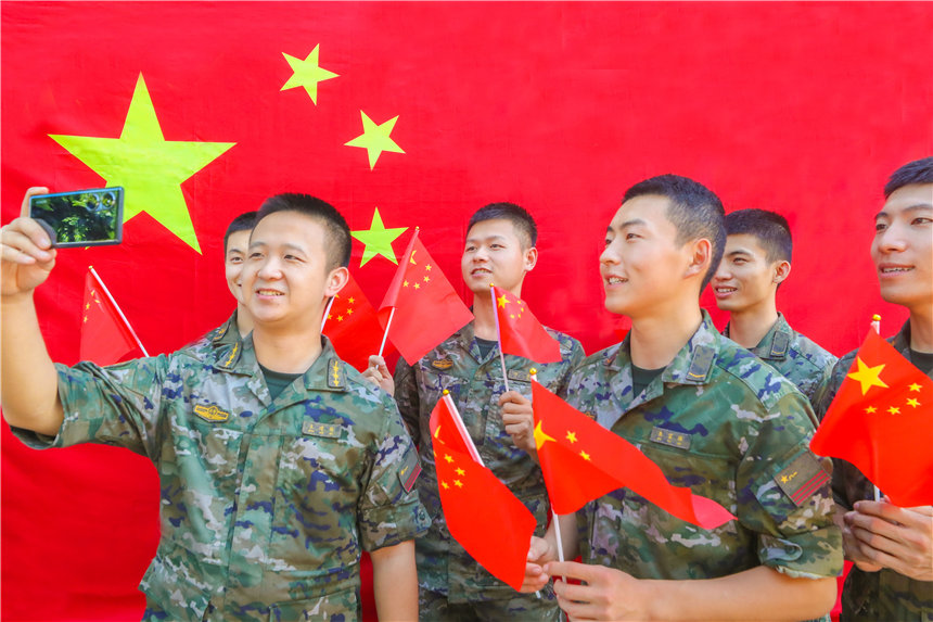 武警官兵與國旗合影，分享國慶喜悅。李東攝