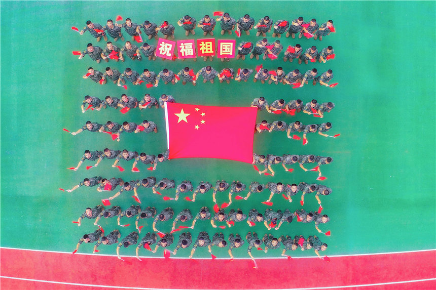 武警官兵與國旗合影，祝福祖國。李東攝