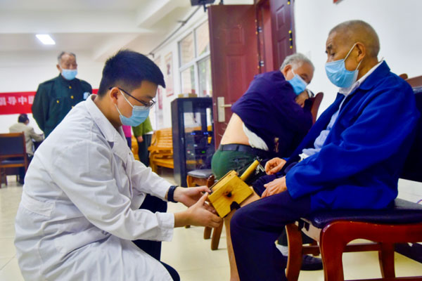 為老人進(jìn)行艾灸治療。陶涵攝