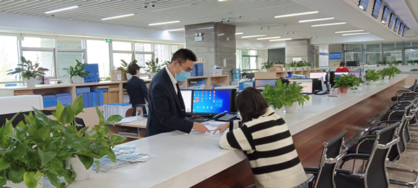 云陽縣行政審批大廳工作人員向建筑公司介紹分階段辦理施工許可證。云陽縣住建委供圖