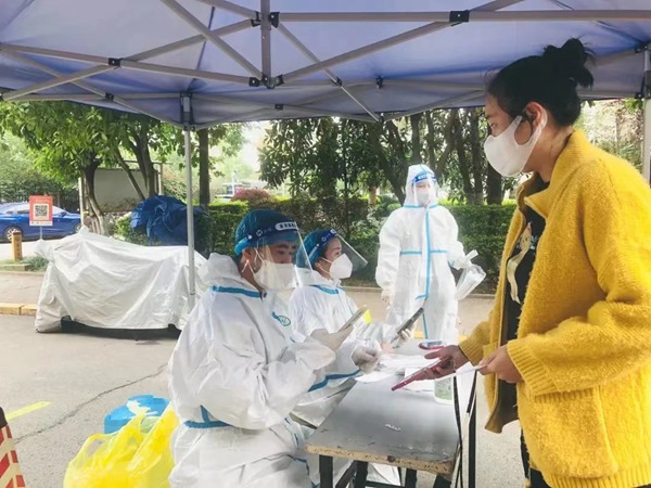 重慶市地產(chǎn)集團黨員冉淵（左一）協(xié)助社區(qū)進行核酸檢測信息錄入工作。重慶市地產(chǎn)集團供圖
