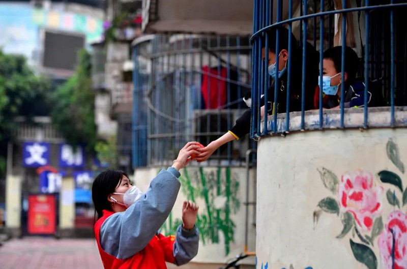 11月18日，南岸區(qū)長(zhǎng)生橋鎮(zhèn)桃花橋社區(qū)移民小區(qū)，一位小朋友為正在小區(qū)巡查的大學(xué)生志愿者李江玲送上了一個(gè)蘋果。此次共有35名來自重慶多所高校的志愿者參加到長(zhǎng)生橋鎮(zhèn)的疫情防控工作中。王雄 攝