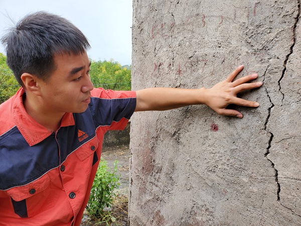 《調(diào)查房屋裂縫》。10月17日，南江地質(zhì)隊(duì)駐守地質(zhì)隊(duì)員陳昊在開(kāi)州區(qū)白鶴街道棕陡坪滑坡調(diào)查居民房屋裂縫。彭向東攝