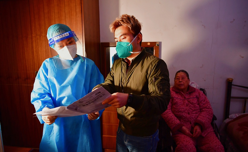 社區(qū)工作人員和醫(yī)護人員在轄區(qū)宣傳疫苗接種。周舸攝