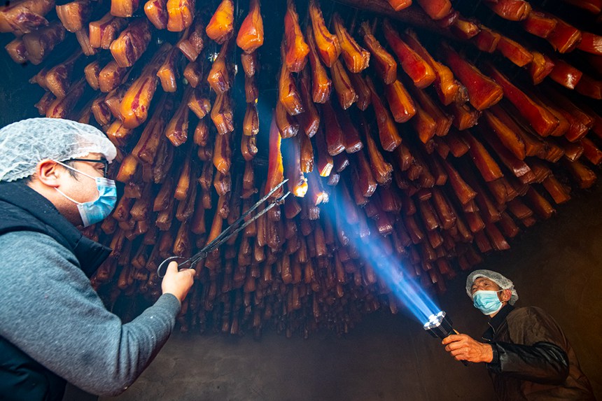 村民在烤臘腸。?冉孟軍攝