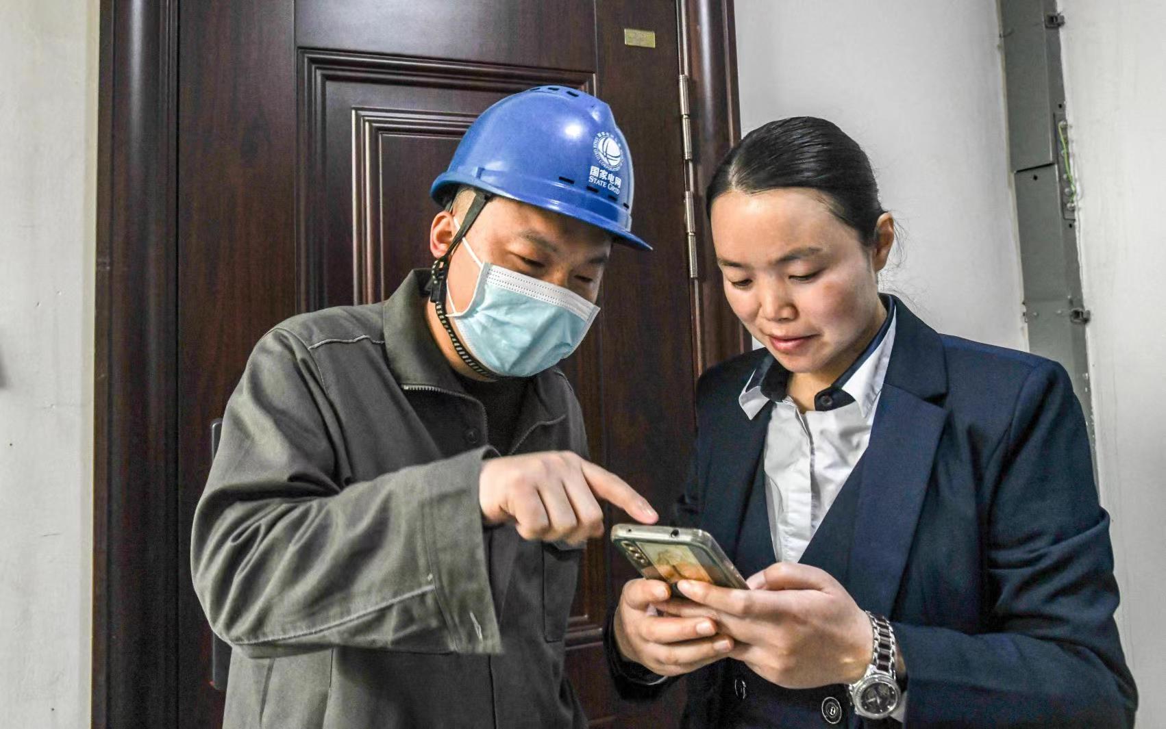 國網(wǎng)江津區(qū)供電公司員工向客戶講解二維碼的用途。王化全 攝