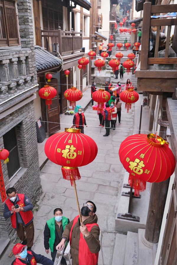 志愿者們正在為黃葛古道敦厚坡段的傳統(tǒng)民居貼春聯(lián)，掛燈籠。郭旭攝