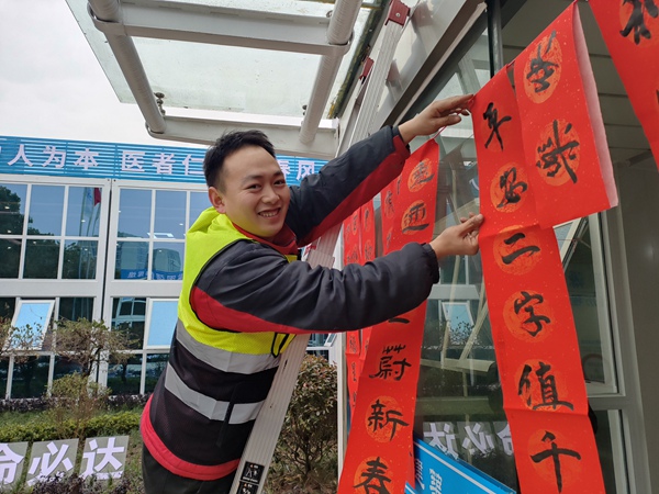 建設(shè)者將寫好的春聯(lián)掛上。