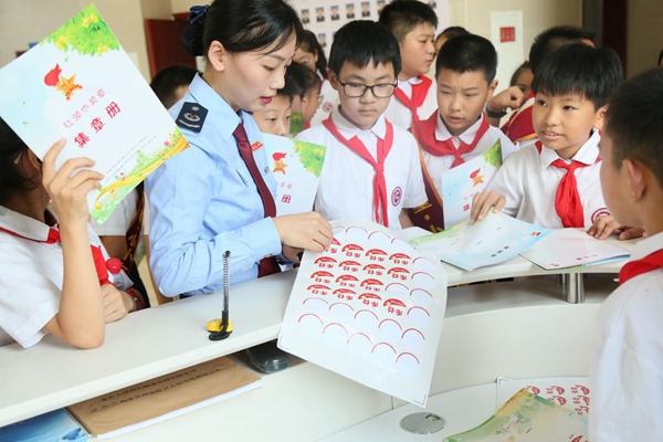 開(kāi)州區(qū)稅務(wù)人員為回答正確稅收問(wèn)題的學(xué)生粘貼禾兌章。譚銳攝