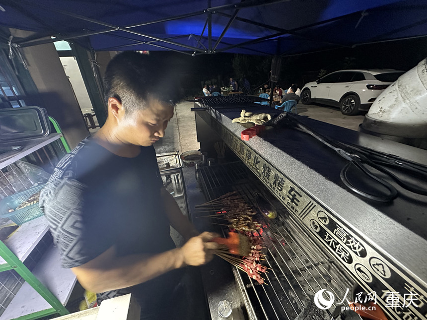 夜晚，方俊在農(nóng)家樂(lè)為游客提供燒烤服務(wù)。 人民網(wǎng)記者 劉政寧攝