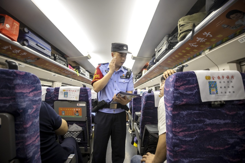 黃同川在列車上向旅客開展安全宣傳。胡勇攝