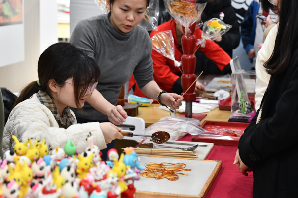 非遺糖畫師指導(dǎo)學(xué)生制作糖畫。鄒樂攝