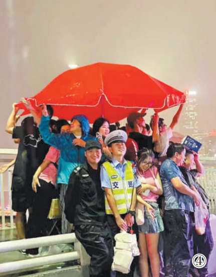 重慶市公安局江北區(qū)分局交巡警支隊(duì)輔警夏英柯在執(zhí)勤中偶遇暴雨，與市民、游客一同避雨。重慶市公安局江北區(qū)分局供圖