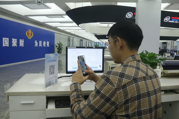 在璧山區(qū)辦稅服務(wù)廳自助辦稅區(qū)，納稅人正在掃描“代開發(fā)票稅率表”二維碼。梅渝攝