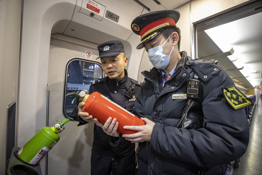 彭聰（左一）在列車(chē)長(zhǎng)的配合下，對(duì)列車(chē)配備的滅火器進(jìn)行檢查。胡勇攝