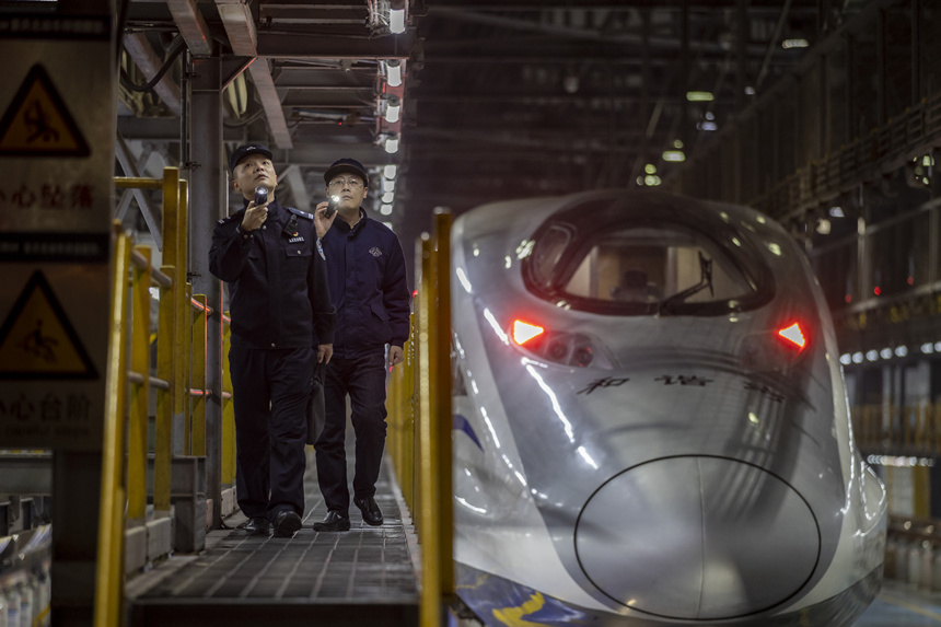 彭聰（左一）在重慶北動(dòng)車(chē)所工作人員的配合下，對(duì)檢修庫(kù)作業(yè)線上的電路阻燃絕緣防護(hù)進(jìn)行檢查。胡勇攝