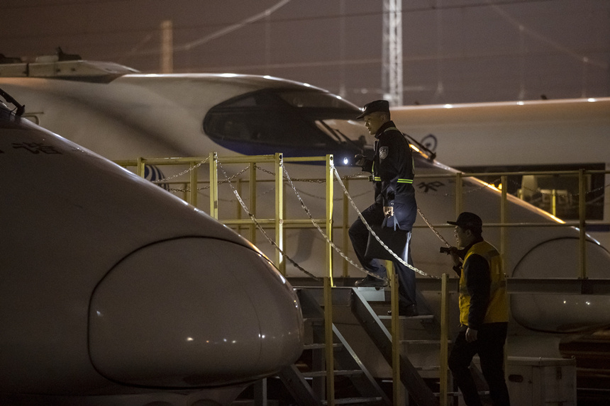 彭聰（左一）在重慶北動(dòng)車(chē)所工作人員的配合下，爬上工作梯，對(duì)停放在存車(chē)場(chǎng)的列車(chē)進(jìn)行巡視。胡勇攝