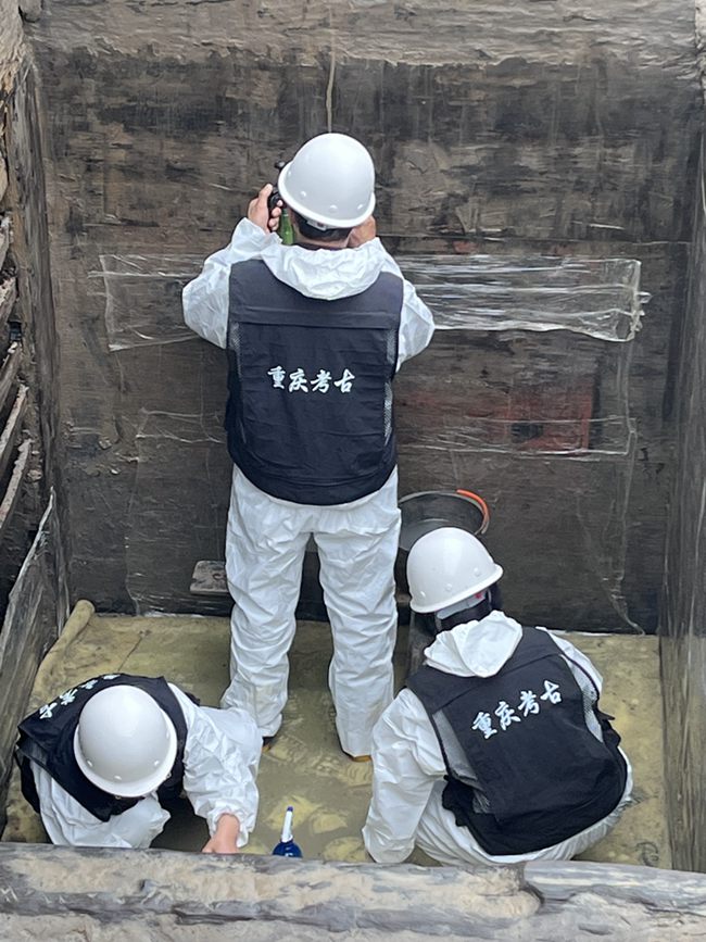 考古人員在墓內清理槨板壁畫。黃偉 攝