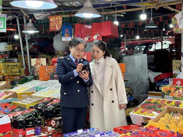 江津區(qū)稅務(wù)人員到雙福國際農(nóng)貿(mào)城輔導(dǎo)商戶使用“農(nóng)品慧”平臺。王露洪攝