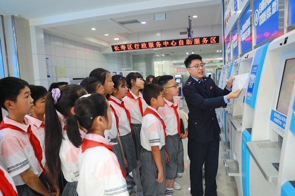 在長壽區(qū)辦稅服務(wù)廳，同學們正認真聽稅務(wù)人員講解發(fā)票代開機的操作步驟和發(fā)票的相關(guān)知識。袁洪昊攝
