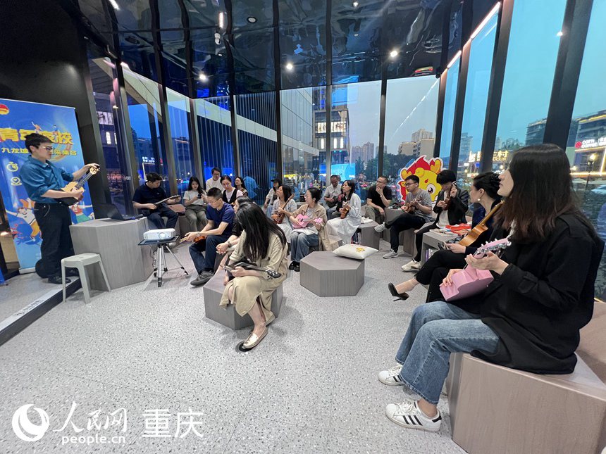 九龍坡區(qū)萬象書屋圓形劇場區(qū)里，學(xué)員們聚精會神聆聽老師講解尤克里里的構(gòu)成。 人民網(wǎng)記者 胡虹攝