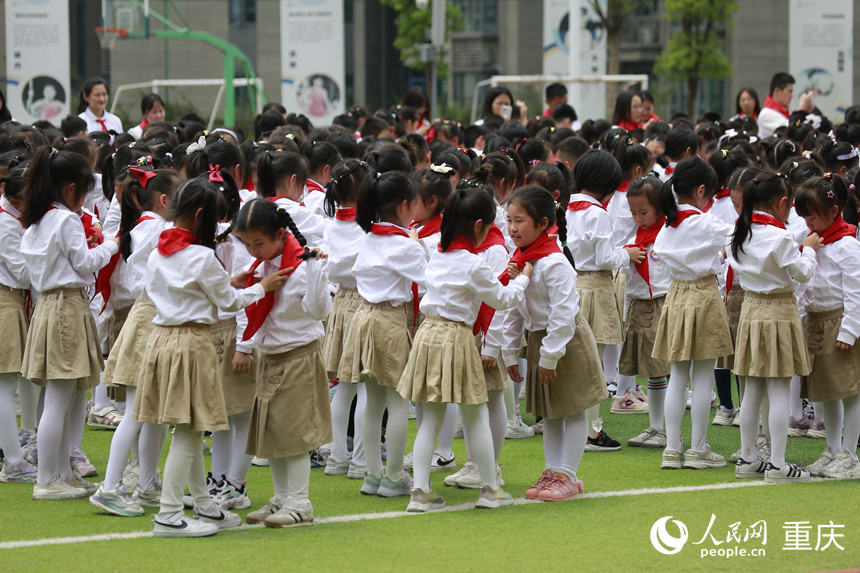 高年級學生為新入隊的少先隊員佩戴紅領(lǐng)巾。人民網(wǎng)記者 劉政寧攝