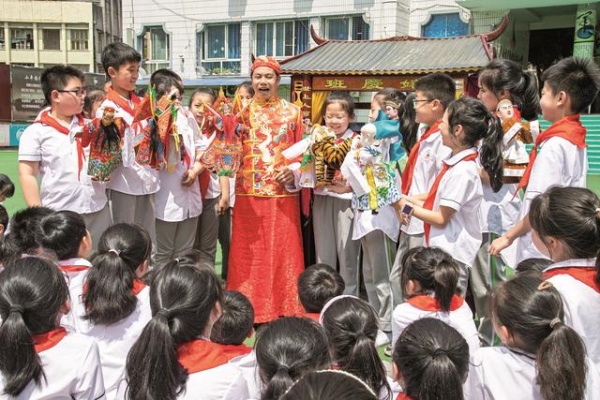 非遺傳承人張賢光給學(xué)生講解手掌木偶戲表演技藝。廣安區(qū)融媒體中心供圖