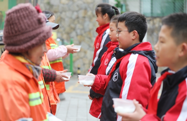 學(xué)生志愿者為社區(qū)清潔工送元宵節(jié)湯圓。九龍坡區(qū)火炬小學(xué)供圖