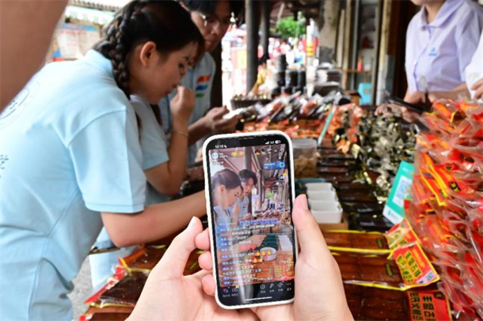 團(tuán)隊(duì)成員在“彭氏火烤豆干”門店前直播展示 通訊員 王青青 供圖