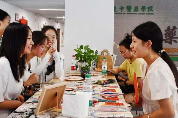 中藥學(xué)院迎新現(xiàn)場(chǎng)，新生和家長(zhǎng)們對(duì)各種中草藥文創(chuàng)產(chǎn)品興趣濃厚。重慶中醫(yī)藥學(xué)院供圖
