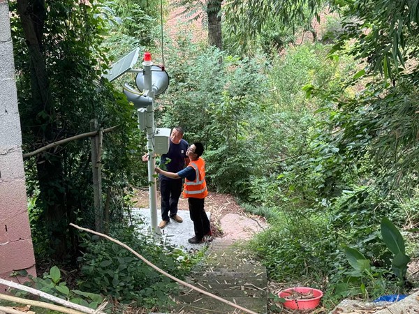 《人防+技防 防災(zāi)更穩(wěn)當(dāng)》。6月24日，巫山縣銅鼓鎮(zhèn)副鎮(zhèn)長(zhǎng)劉勇（左）、地質(zhì)駐守隊(duì)員王忠凌到竹園村劉家老屋滑坡點(diǎn)，檢查新安裝的地質(zhì)災(zāi)害監(jiān)測(cè)設(shè)備運(yùn)行是否正常。人防+技防，才讓地質(zhì)災(zāi)害防治工作更加踏實(shí)穩(wěn)妥。謝清艮攝