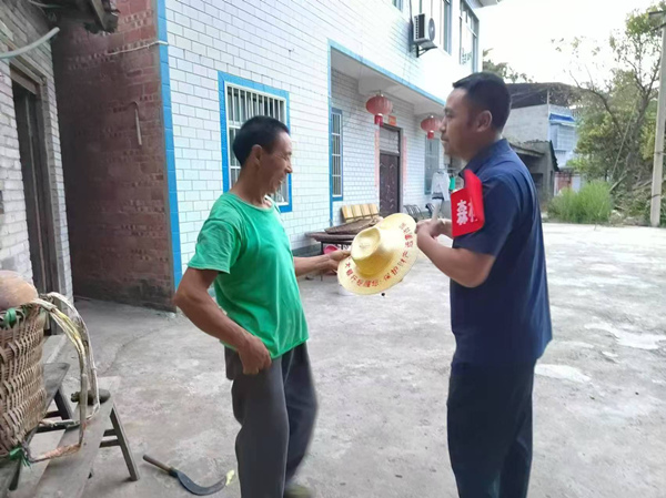 光大銀行重慶分行駐奉節(jié)縣長凼村駐村書記向村民贈送印有防詐宣傳語的農(nóng)用草帽。光大銀行重慶分行供圖