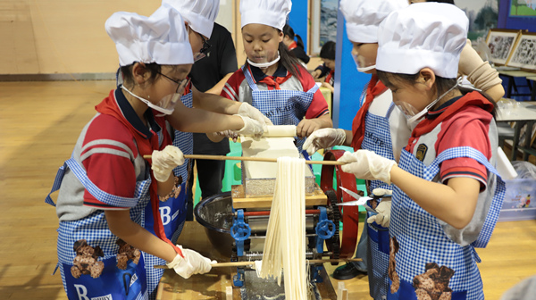 展評(píng)活動(dòng)現(xiàn)場(chǎng)，學(xué)生用壓面機(jī)制作面條。重慶市萬(wàn)盛經(jīng)開區(qū)教育局供圖