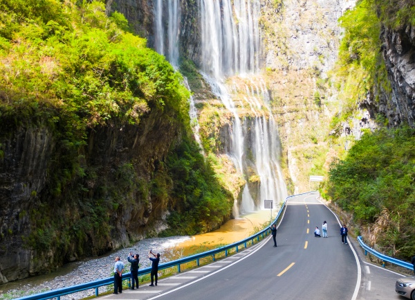 行人駐足觀看飛瀑美景。熊威攝