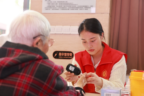 義診中，志愿者為老年人做血糖檢測。曾英豪攝