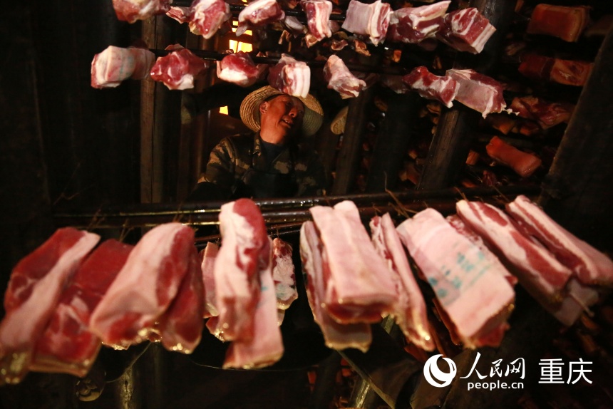 工人將腌制好的豬肉掛入炕房。人民網(wǎng)記者 劉政寧攝