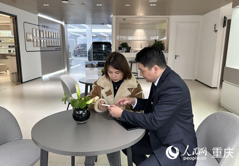 王女士在工作人員的指引下用手機(jī)辦理新車上牌業(yè)務(wù)。人民網(wǎng)記者 劉政寧攝