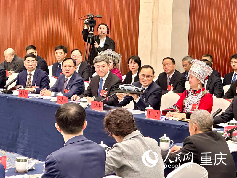 2025全國兩會期間,朱華榮在重慶代表團開放團組會議上展示“重慶造”汽車模型。人民網(wǎng)記者 劉政寧攝