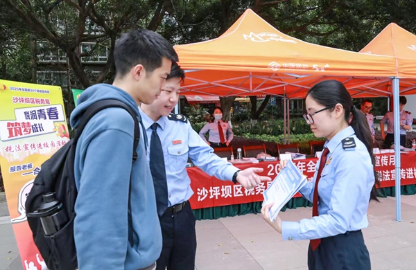 沙坪壩區(qū)稅務人員在四川外國語大學設置宣傳點，向往來學生發(fā)放宣傳冊，邀請其參與合規(guī)經(jīng)營情景模擬，樹立合規(guī)經(jīng)營意識。郭亞玲 攝
