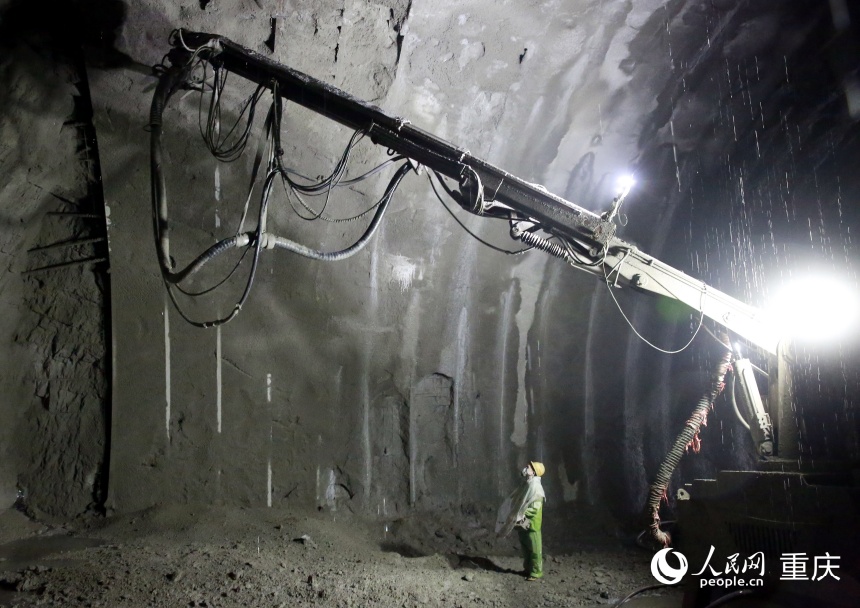 施工人員身穿雨衣正在進(jìn)行噴射混凝土作業(yè)。人民網(wǎng)記者 劉政寧攝